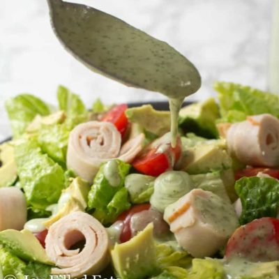 spoon drizzling paleo ranch dressing onto salad close up