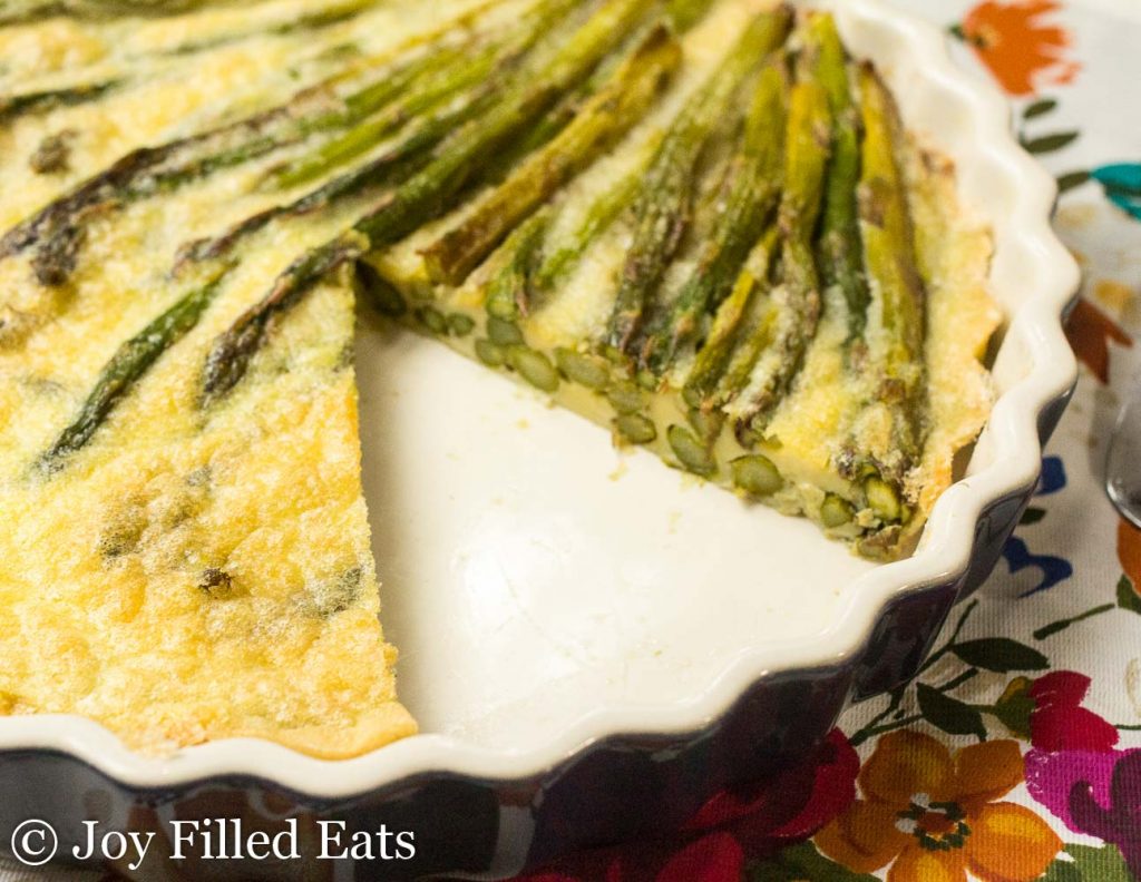 pie plate of asparagus quiche with slice missing