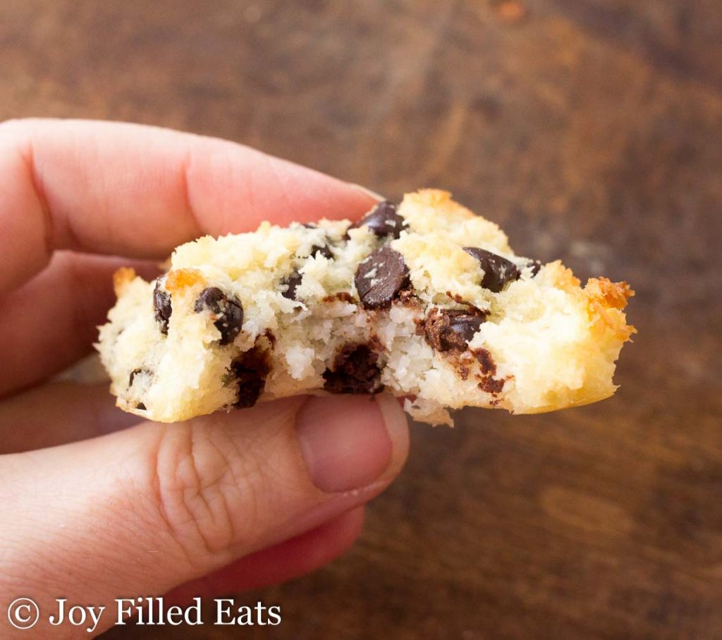 hand holding chocolate chip coconut macaroon with large bite missing