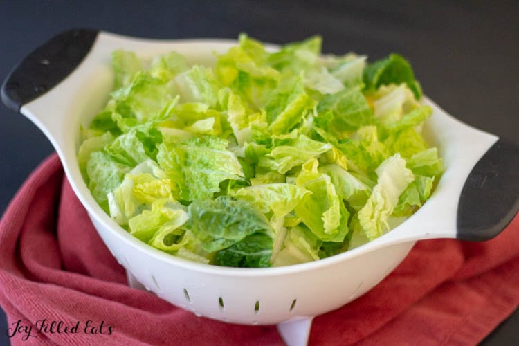 chopped romaine lettuce in a white colander close up