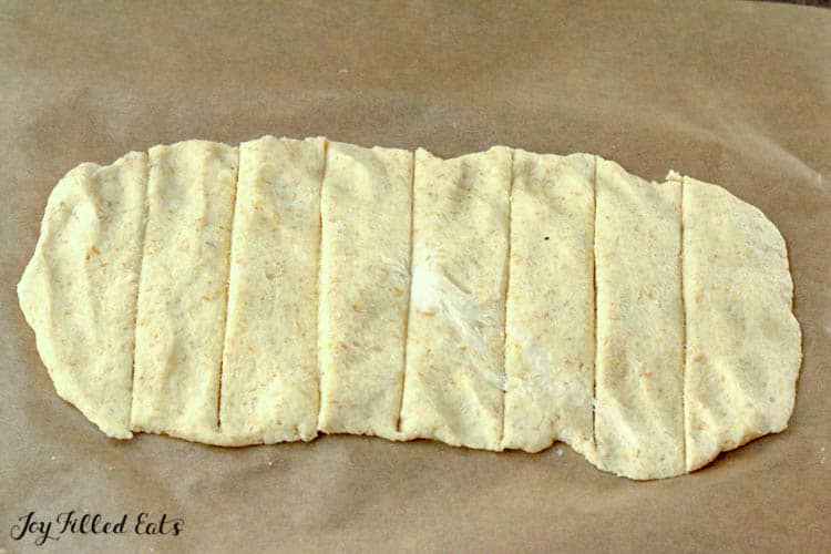 rolled out breadstick dough on parchment paper with perforated lines for cutting