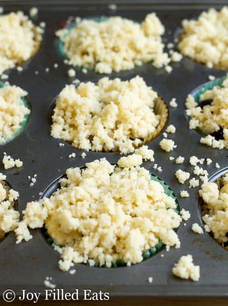 muffin tin full of batter topped with crumb topping
