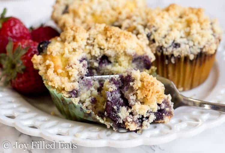 blueberry muffin with crumb topping being cut with a fork