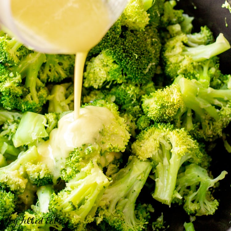 close up of pouring the lemon garlic dressing over the garlic broccoli side dish recipe