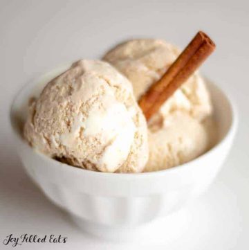Cinnamon Roll Ice Cream with a Cream Cheese Icing Swirl in a white bowl with a cinnamon stick