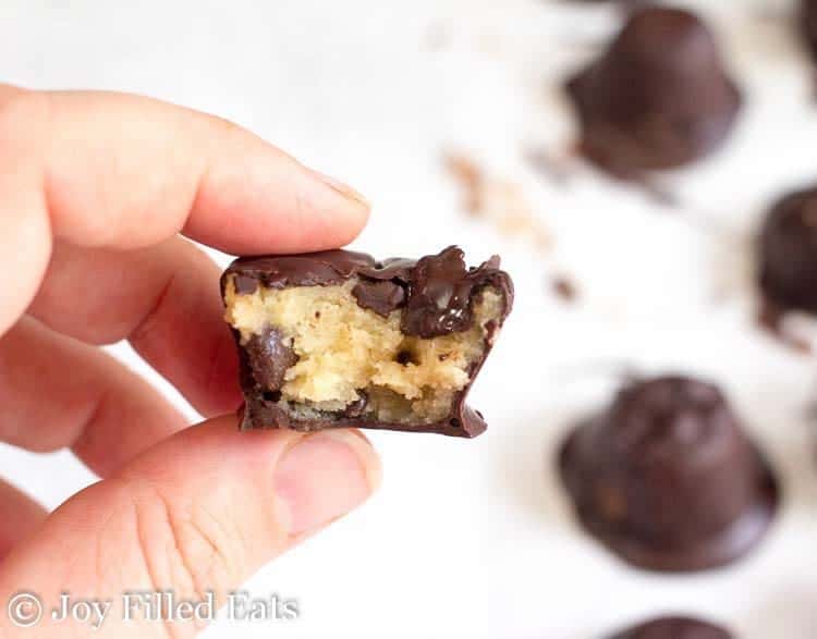 A hand holding a Frozen Cookie Dough Bites with a bite out of it