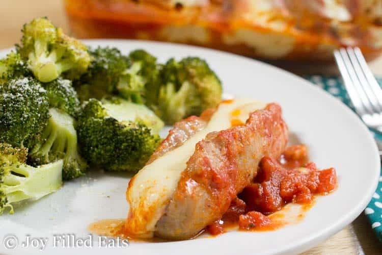 stuffed sausage next to broccoli on a white plate