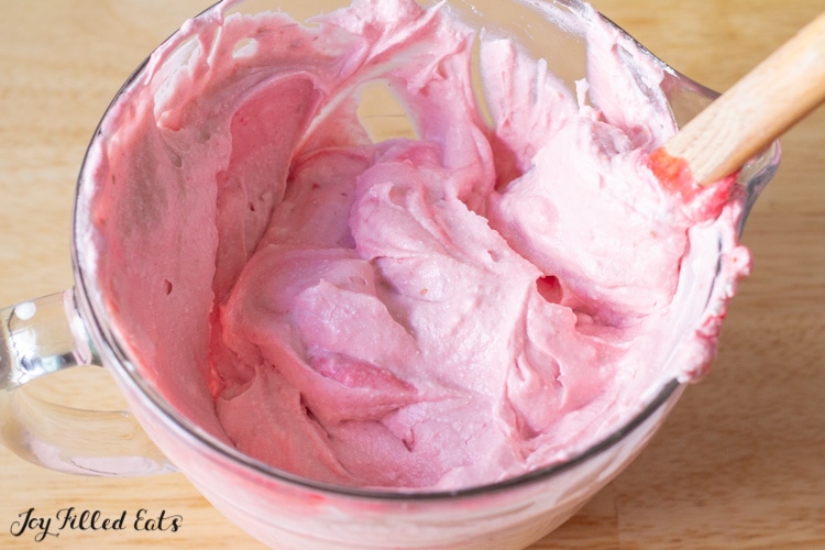 raspberry frosting in a measuring cup with spatula