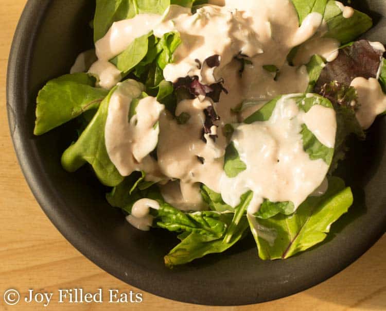 bowl of mixed greens topped with creamy garlic salad dressing from above