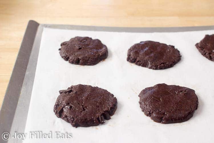 round shaped chocolate cookie dough placed on a parchment lined sheet pan