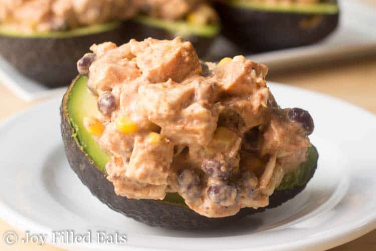 southwest chicken salad stuffed avocado on a white plate close up