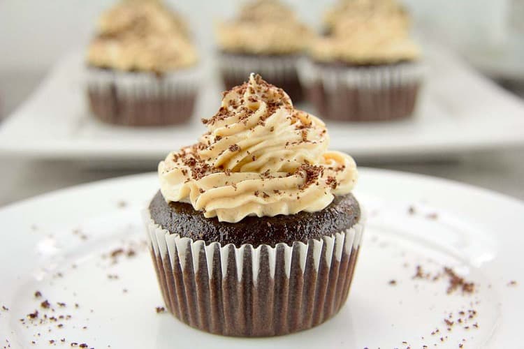 close up on chocolate cupcake on a white plate topped with peanut butter frosting