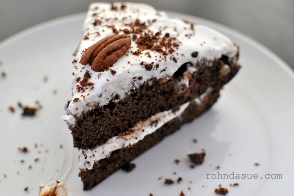 slice of two layer chocolate praline cake topped with frosting and a whole praline