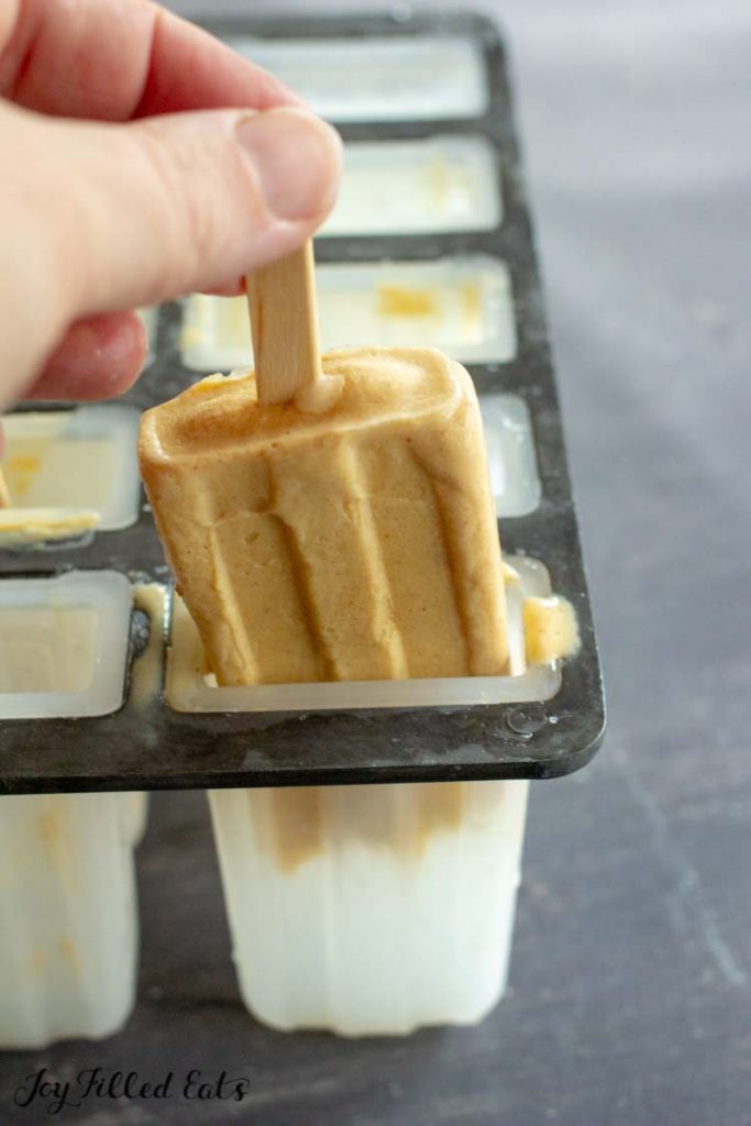 hand removing pumpkin ice cream bar from Popsicle mold