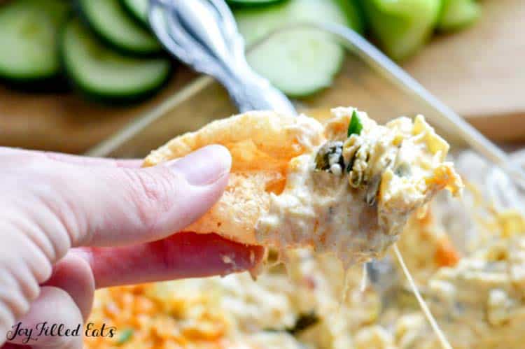 hand holding chip with bite of tex-mix poblano artichoke dip