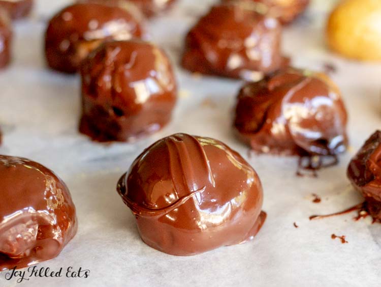 peanut butter balls coated in chocolate lined on parchment paper