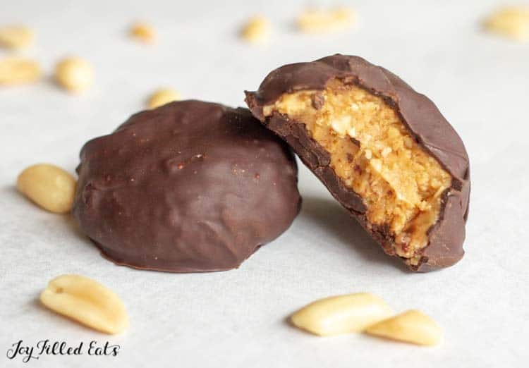 one of the keto peanut butter balls with a bite out of it leaning on another one