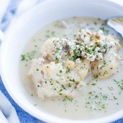 close up on white bowl of biscuits and gravy with spoon
