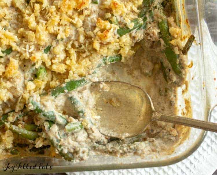 overhead view of healthy green bean casserole with corner piece missing with spoon sticking in dish close up