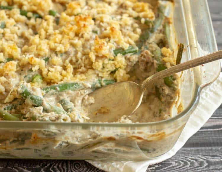 healthy green bean casserole with corner piece missing with spoon sticking in dish close up