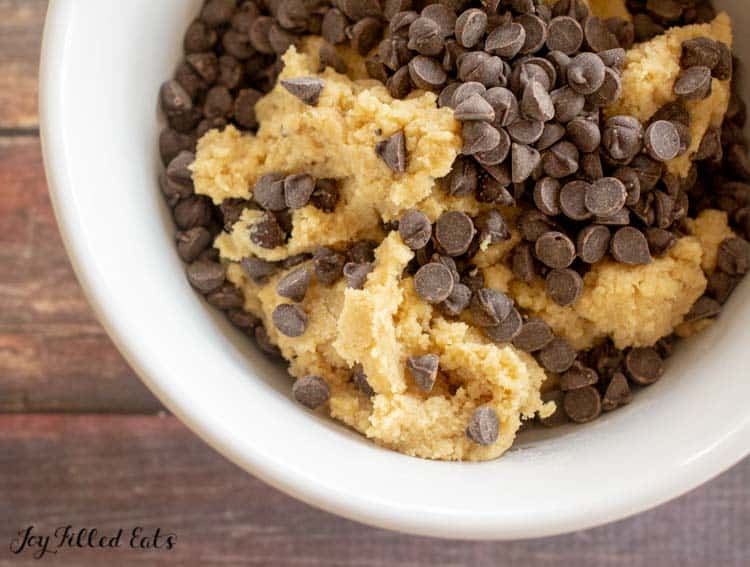 bowl of eggless cookie batter in mixing bowl topped with chocolate chips