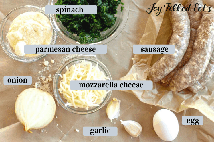 Keto Sausage Ball ingredients including sausage, spinach, Parmesan cheese, mozzarella cheese, onion, garlic and an egg