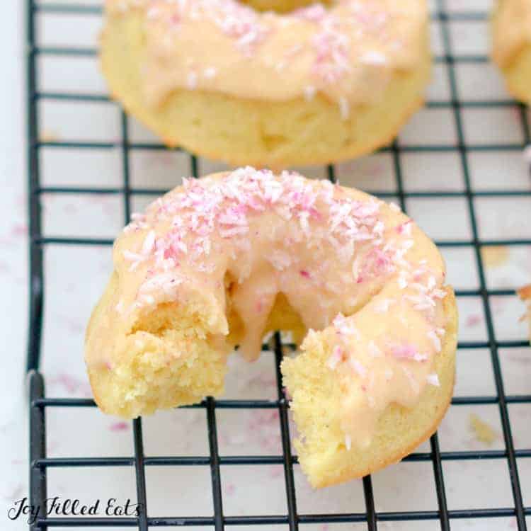 vanilla donut with toasted coconut glaze missing a large bite on a cooling rack