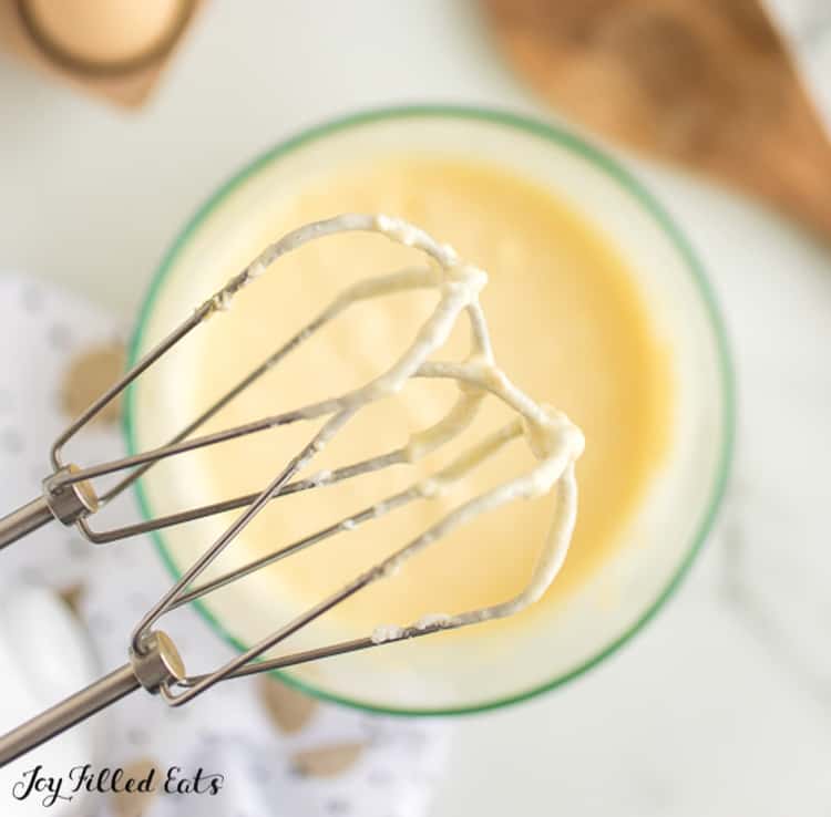 close up on hand mixer beaters covered in cheesecake batter
