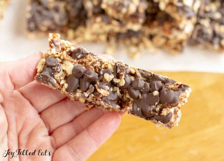 hand holding a no bake keto granola bar topped with chocolate chips