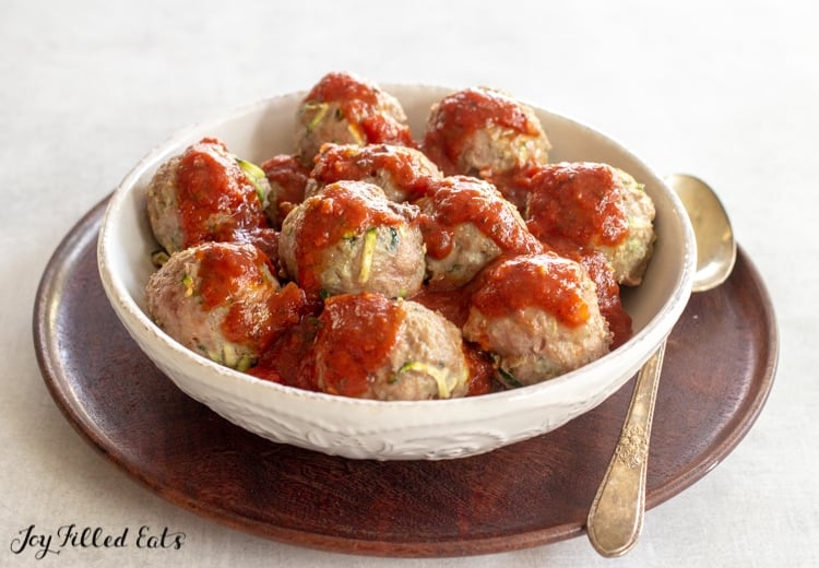 baked turkey meatballs in a bowl covered in marinara sauce place with a spoon