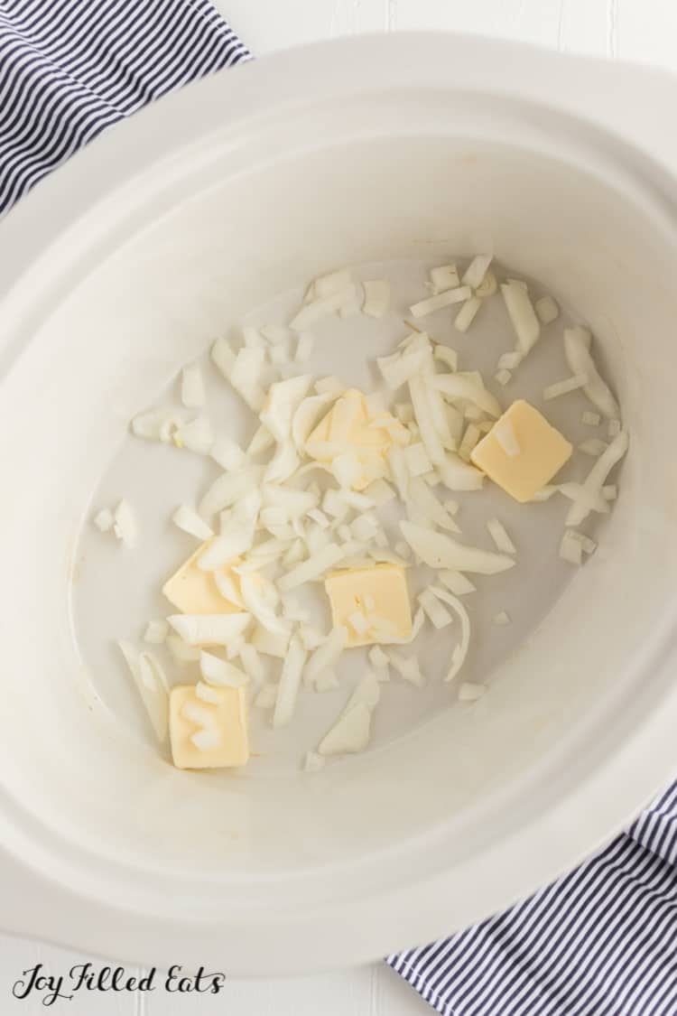 butter and chopped onions layered on the bae of a slow cooker