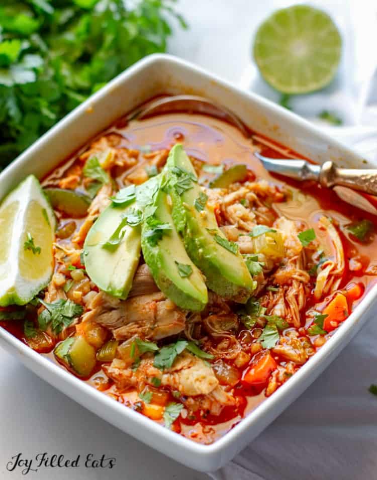 bowl and spoon of tex-mex chicken & rice soup topped with avocado slices