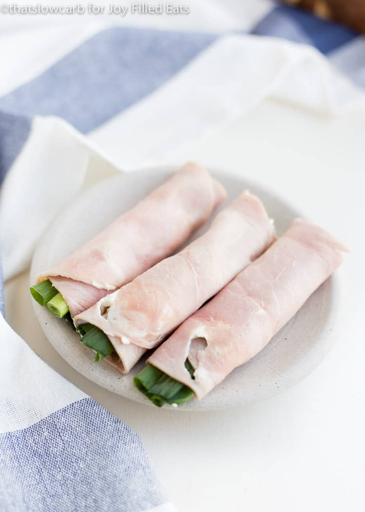 three ham and cream cheese roll ups on a white plate