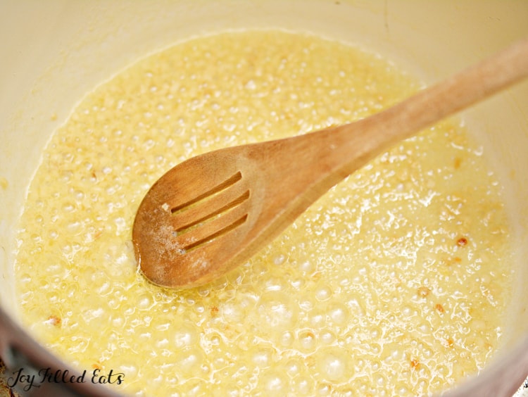 simmering ingredients in saucepan with wooden spoon