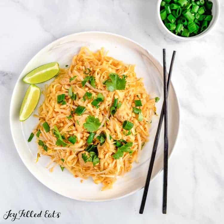 Keto pad thai with chicken served with lime wedges and chopsticks from above