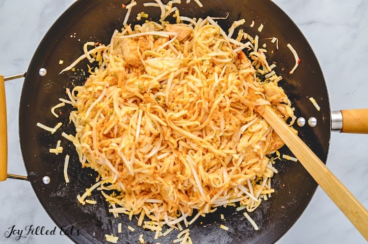 chicken and noodles together in skillet with wooden spoon