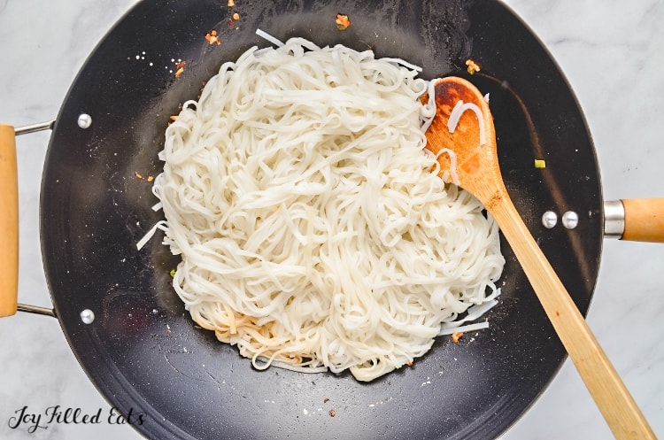 noodles cooking in skillet with wooden spoon