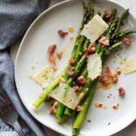 plate of roasted asparagus topped with prosciutto, dijon vinaigrette and cheese shavings