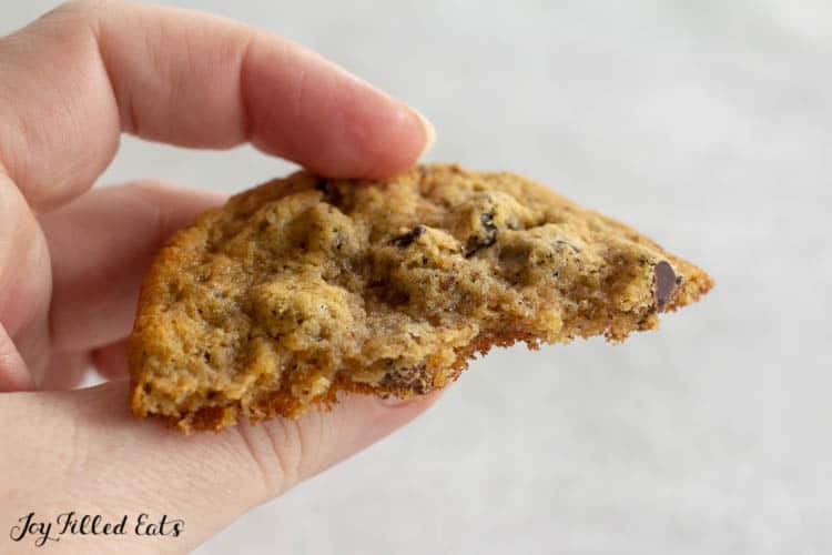 hand holding half an almond flour chocolate chip cookie