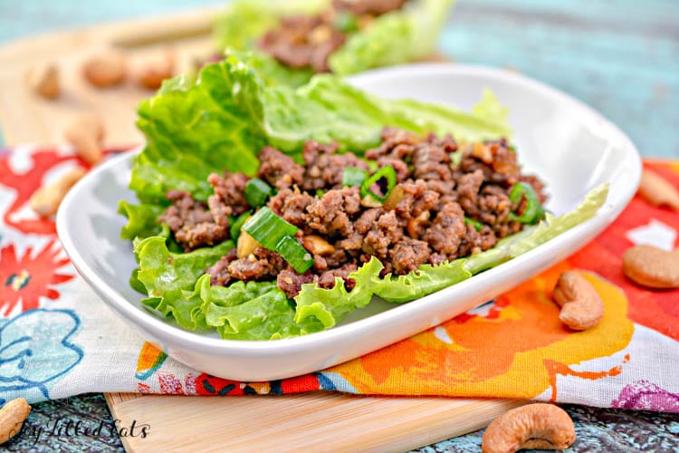 asian lettuce wrap with ground beef placed on a white plate atop a decorative napkin