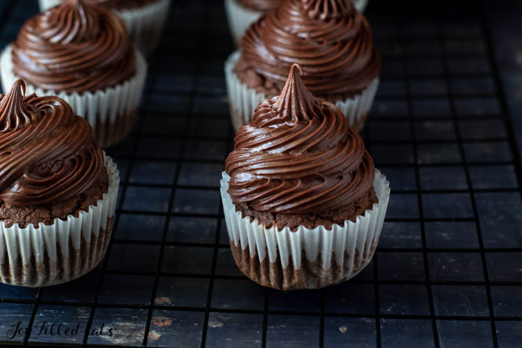 two rows of keto chocolate cupcakes with chocolate cream cheese icing on a cooling rack close up