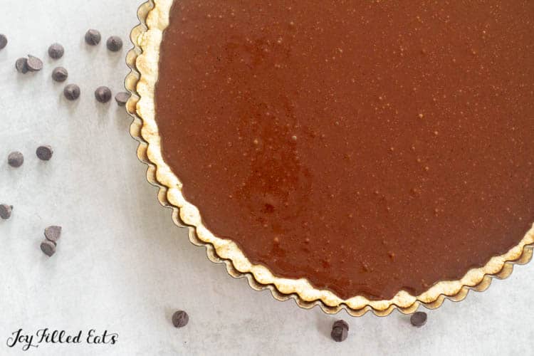 chocolate tart from above in pie plate with chocolate chips scattered on surface