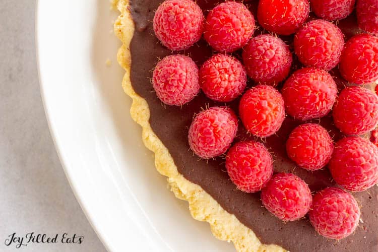 close up of chocolate tart topped with raspberries from above