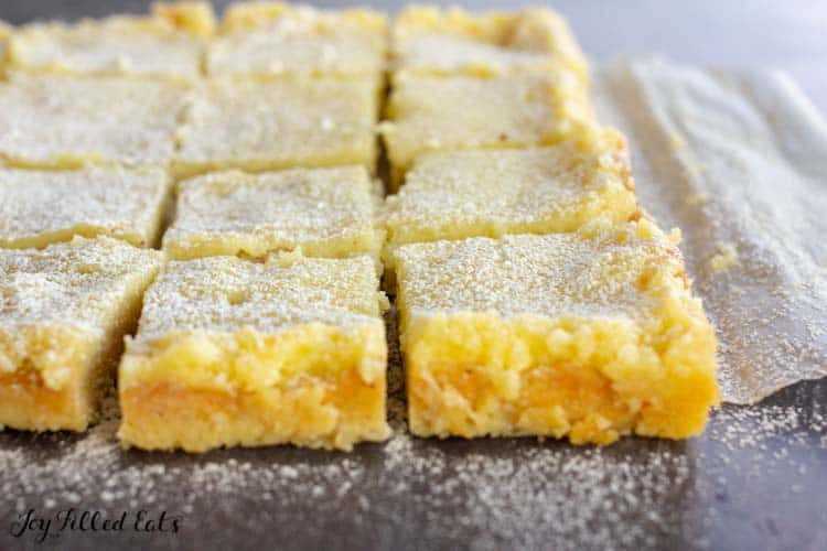 sugar free lemon bars on parchment paper dusted in sweetener close up
