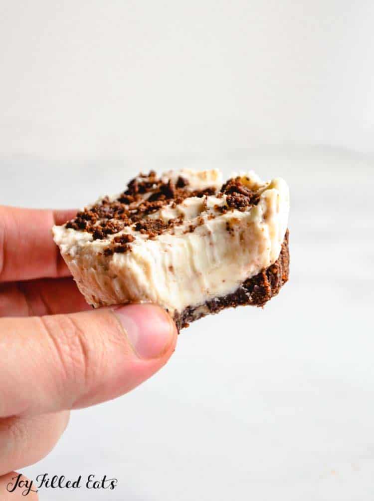 hand hold oreo cheesecake bite with large bite missing