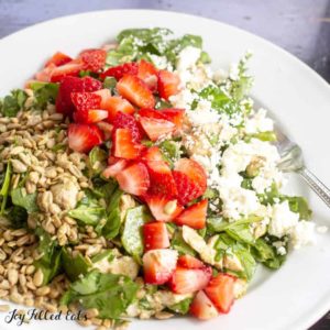 baby spinach salad topped with diced strawberries, feta cheese and sunflower seeds close up