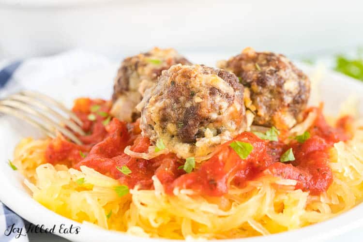 spaghetti squash and sauce topped with keto meatballs on a plate with fork