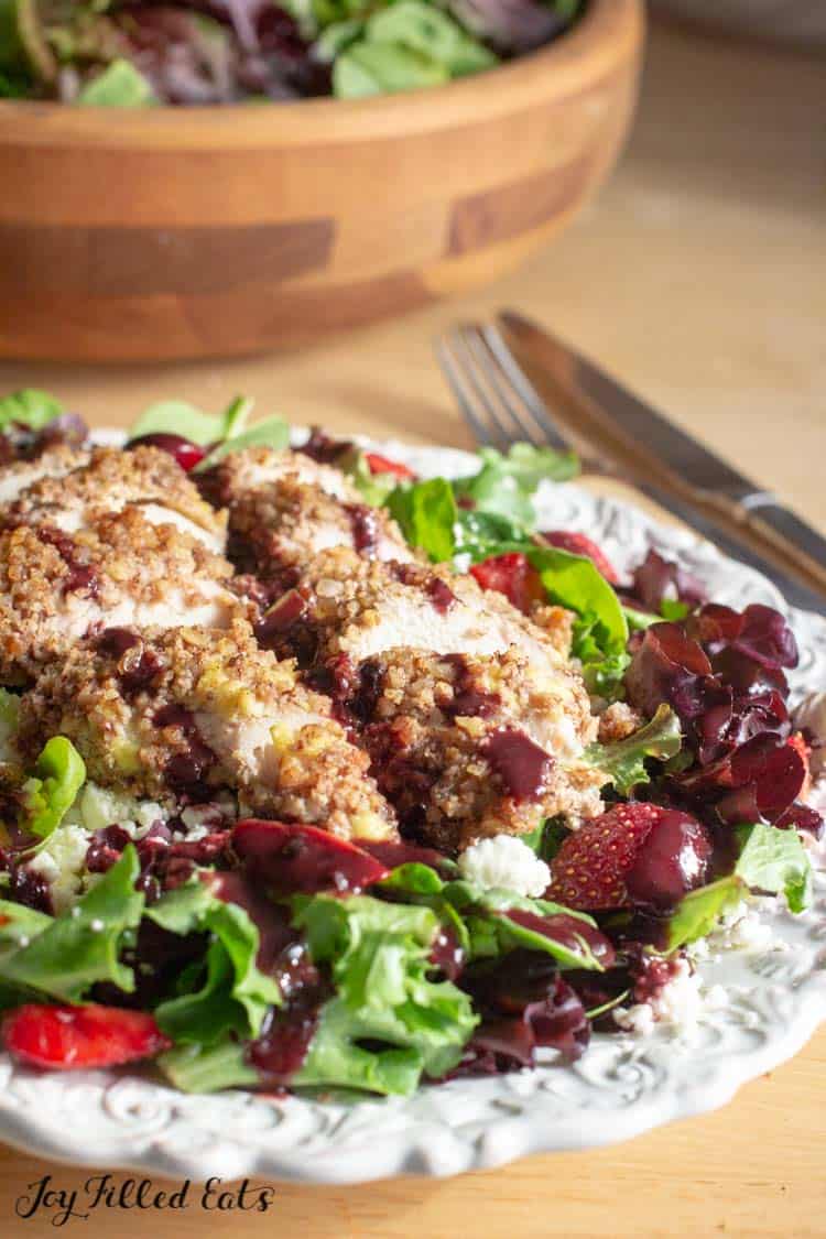 pecan crusted chicken sliced on top a green salad with strawberries