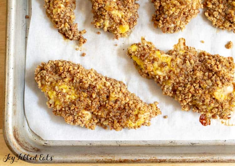 pecan crusted chicken on a parchment lined sheet pan close up