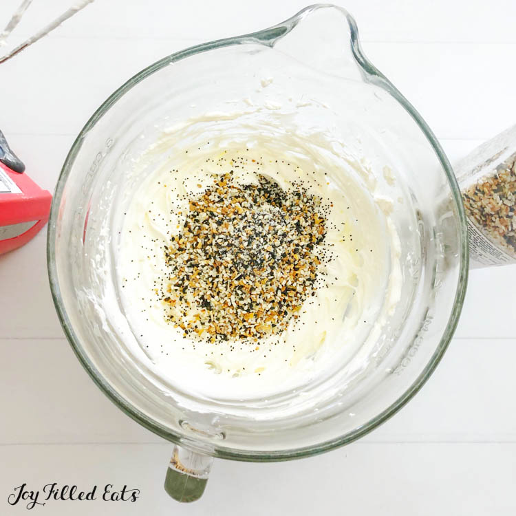 large mixing bowl of everything bagel seasoning on top of dip base, ready to be mixed in
